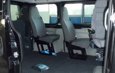 Gulv med sort, fuldlimet tæppe. To passagersæder af typen Jany 801. Elkørestolslås for kørestol uden passager.