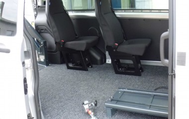 Gulv med sort, fuldlimet tæppe. To passagerstole af typen Jany 801. Retractor kørestolsbespænding.
